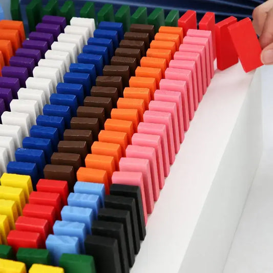 Colorful dominoes set up in a row with a hand placing a red domino—Greater Toys Store