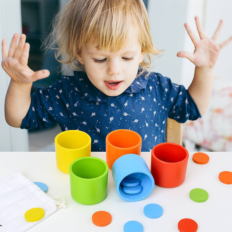 Child playing with colorful cups and circles on a table—Greater Toys Store