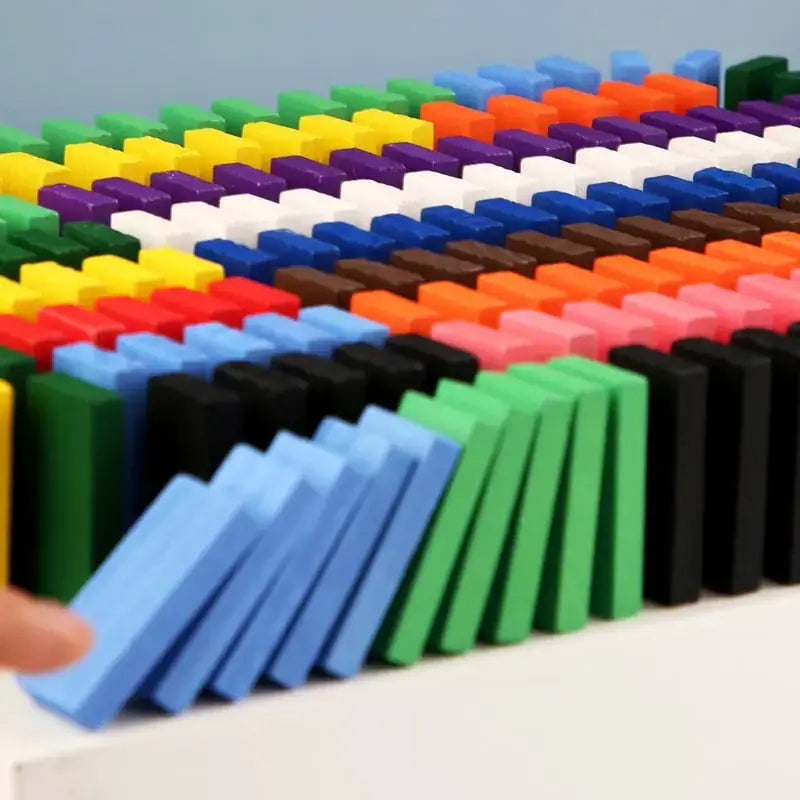 Colorful dominoes set on a light surface with a hand interacting with them —Greater Toys Store